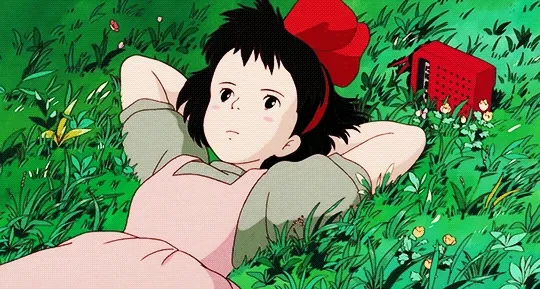 Kiki from Kiki's Delivery Service laying in the grass with a radio