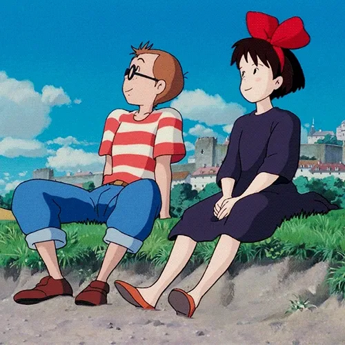 Kiki and Tombo sitting in the grass together, smiling, and looking at the sky